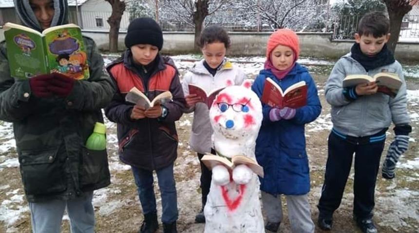 Kardan adam yapıp başında kitap okudular