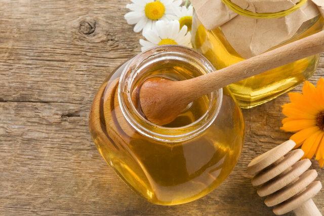 jar of honey and flowers on wood background