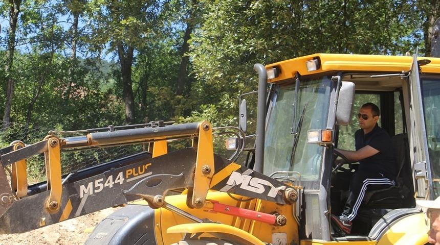 Kaymakam, şehitlik bakım &ccedil;alışmalarında iş makinası kullandı ve peyzaj &ccedil;alışmasına katıldı