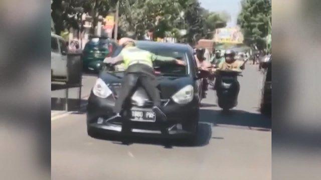 Trafik polisi, kırmızı ışıkta geçen otomobilin kaputuna çıktı