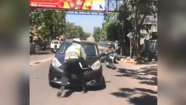 Trafik polisi, kırmızı ışıkta geçen otomobilin kaputuna çıktı