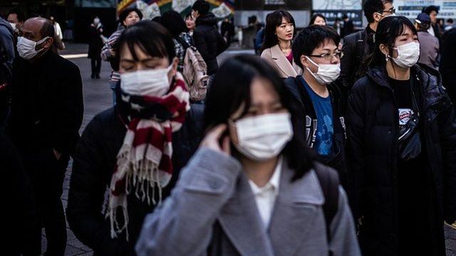 Tokyo'da hastalıklarını başkalarına geçirmemek için maske takan insanlar.