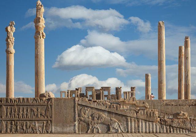 Ruins of Apadana and Tachara Palace behind stairway with bas relief carvings in Persepolis Unesco World Heritage Site against cloudy blue sky in Shiraz, Iran