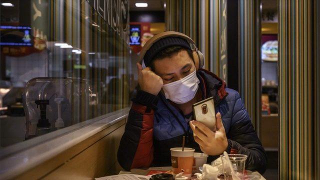 A man wears a protective mask while eating in a McDonald