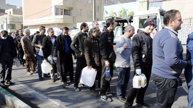 Tahran'da halk Devrim Muhafızları tarafından dağıtılan bedava sıvı dezenfektandan almak için kuyrukta