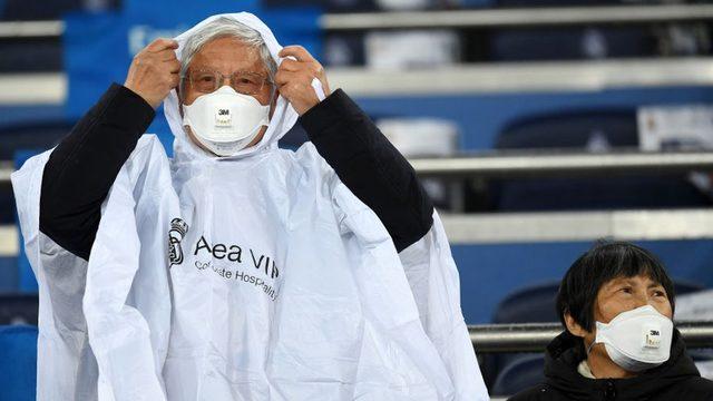 Güney Kore'de bir futbol maçında maskeli taraftarlar oyunu bekliyor