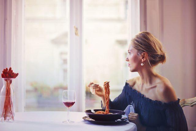woman-sitting-on-chair-while-eating-pasta-dish-1456262