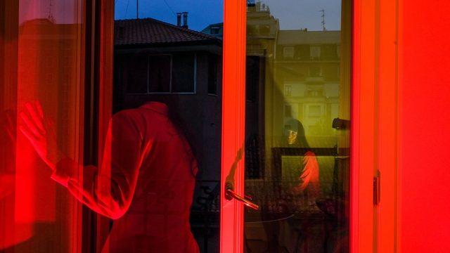 A red-tinted photograph shows Lucia staring outside of her window