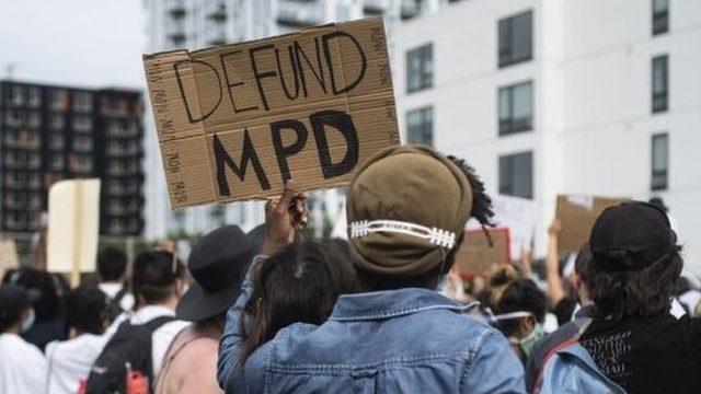 Protesters hold a placard that reads 