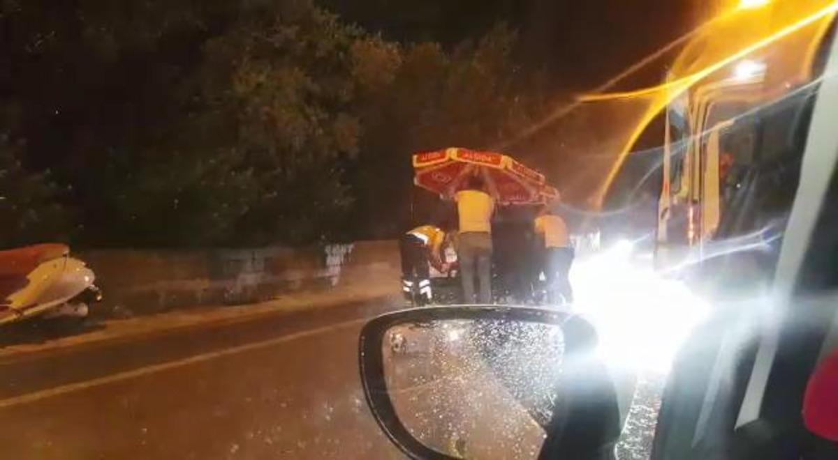 Kazada yaralanan s&uuml;r&uuml;c&uuml;y&uuml;, şemsiye ile yağmurdan korumaya &ccedil;alıştılar