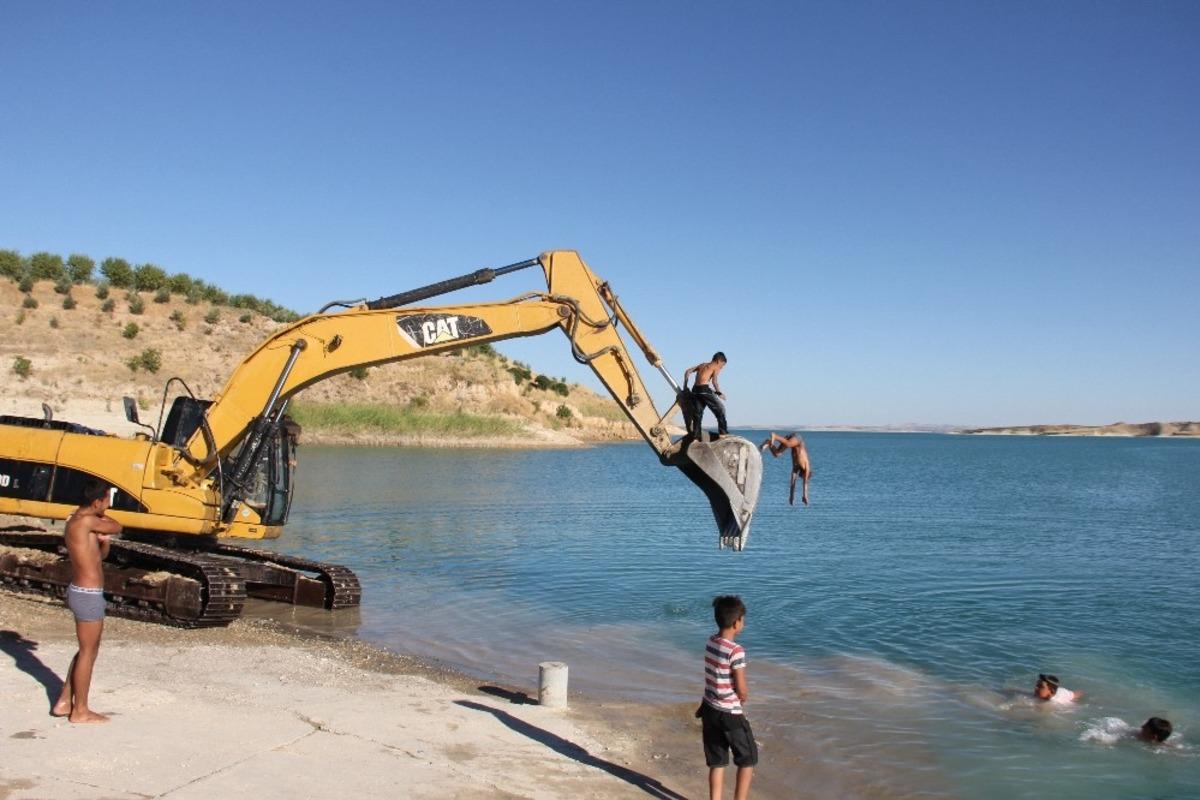 İş makinesi serinleyen &ccedil;ocukların eğlencesine ortak oldu