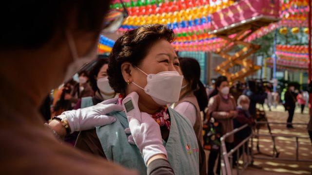 Worshippers wearing face masks have their temperature taken