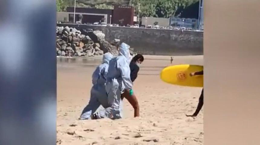 İspanya'da koronavir&uuml;sl&uuml; hasta denize girdi, polis koruyucu giysilerle g&ouml;z altına aldı