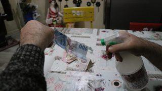 Paraları dezenfektanla yıkayıp sobada kurutuyor