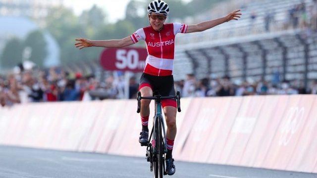 Anna Kiesenhofer celebrates as she rides across the line in the women's road race