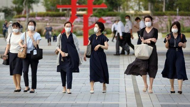 Tokyo'a yürüyen maskeli insanlar