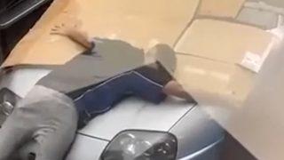 Arabasını doludan korumak için bedenini kullandı! Sosyal medyada eğlenceli anlar yaşattı