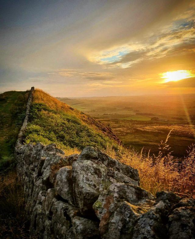 A view of Hadrian's Wall with a sunset in the background