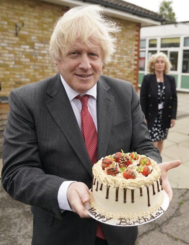 Boris Johnson doğum günü pastasını tutuyor