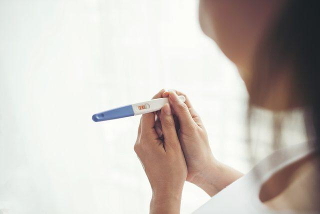 1643821592_young_woman_hand_holding_pregnancy_test