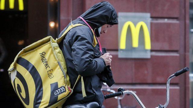 Bir Yandex.Eda yiyecek servisi çalışanı, Moskova merkezindeki McDonald's restoranı önünde görülüyor