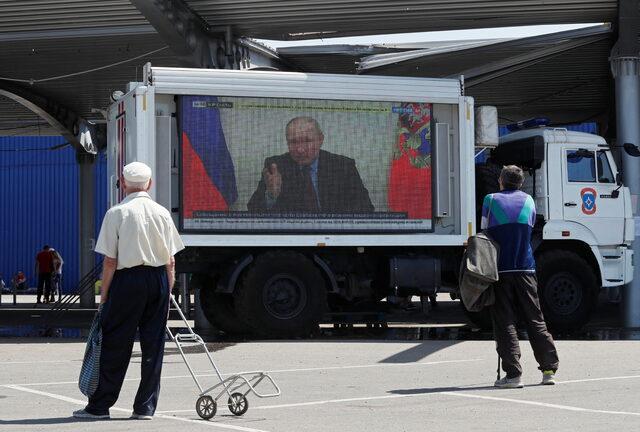 Russian President Vladimir Putin is seen on a screen broadcasting Russian TV news programs in Mariupol