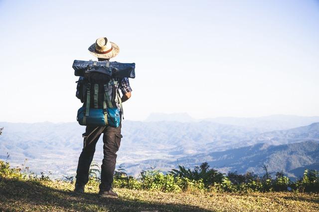 tourist-from-mountain-top-sun-rays-man-wear-big-backpack-against-sun-light_1150-9121