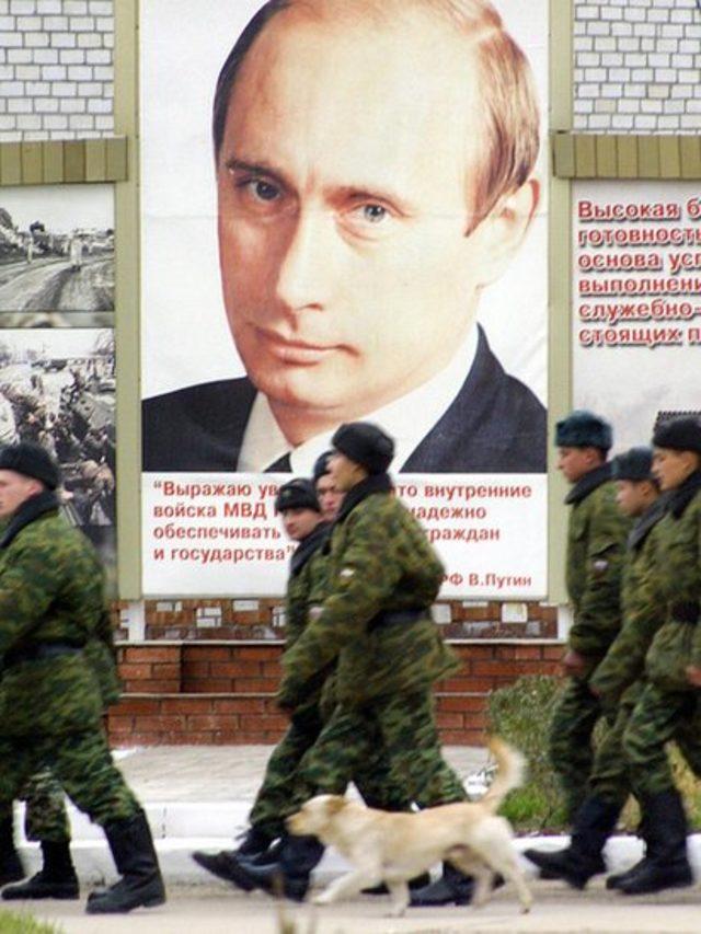 Russian soldiers march next to a giant poster of the Russian President Vladimir Putin at an army barrack in Grozny, Chechnya