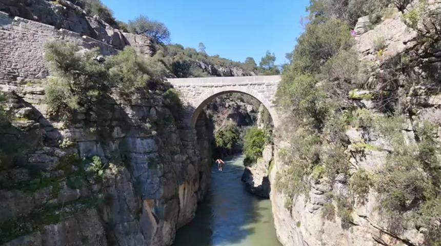 Antalya&rsquo;da 20 metre y&uuml;kseklikteki tarihi k&ouml;pr&uuml;den suya atlayan gen&ccedil; y&uuml;rekleri ağza getirdi