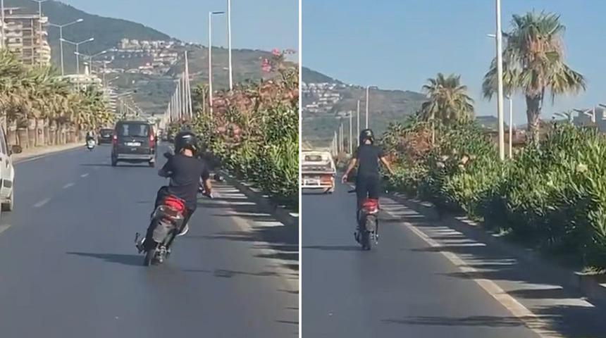 Alanya'da motosiklet &uuml;zerinde ayakta ilerleyen s&uuml;r&uuml;c&uuml;n&uuml;n tehlikeli yolculuğu kamerada