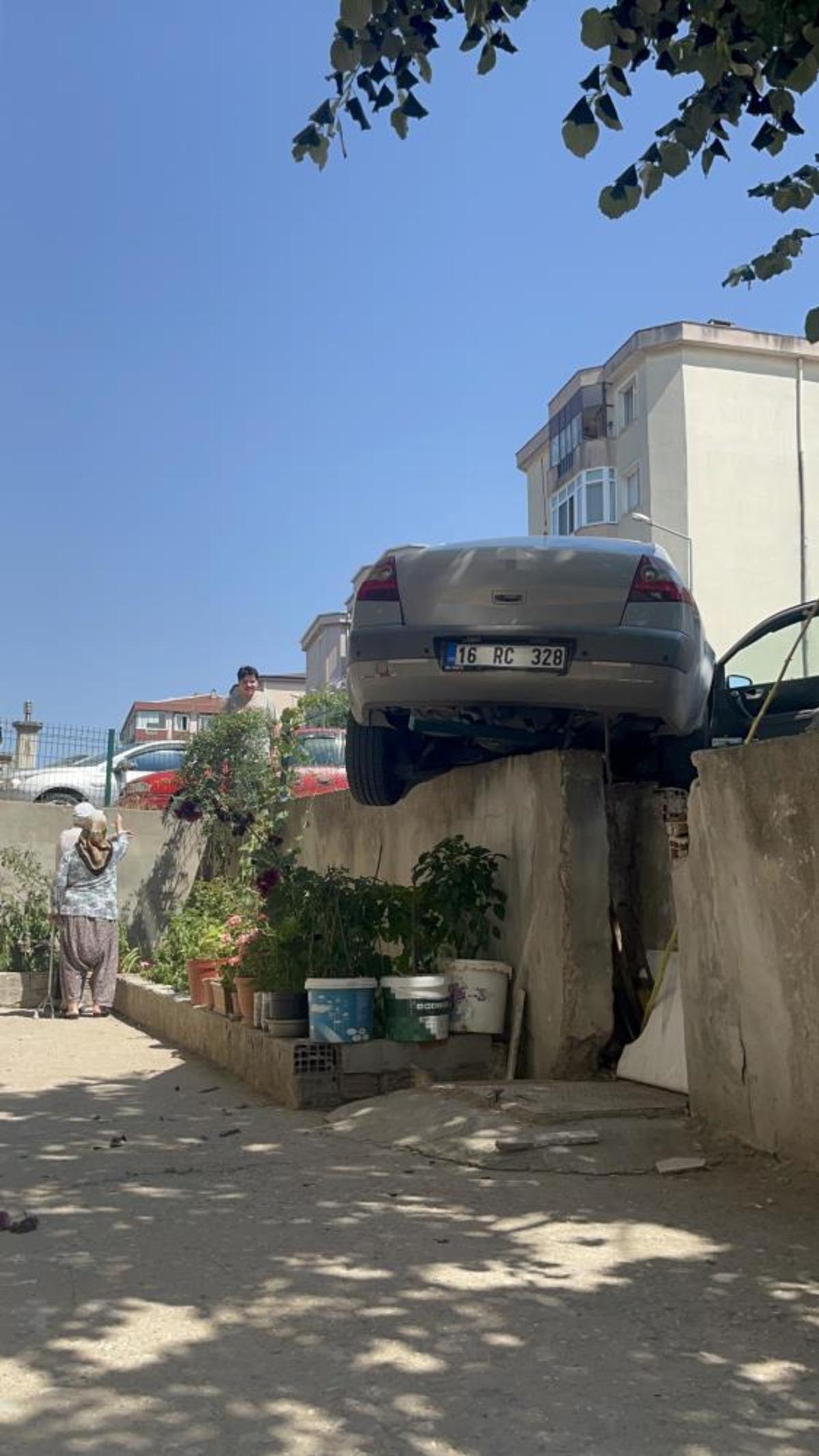 El frenini çekmeyi unuttu, otomobil bahçe duvarında asılı kaldı 1