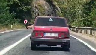 Ayaklarını camdan sarkıtarak trafiği tehlikeye attı
