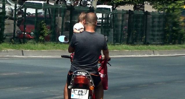 Bir koluyla motosiklet sürdü, diğeriyle çocuk taşıdı