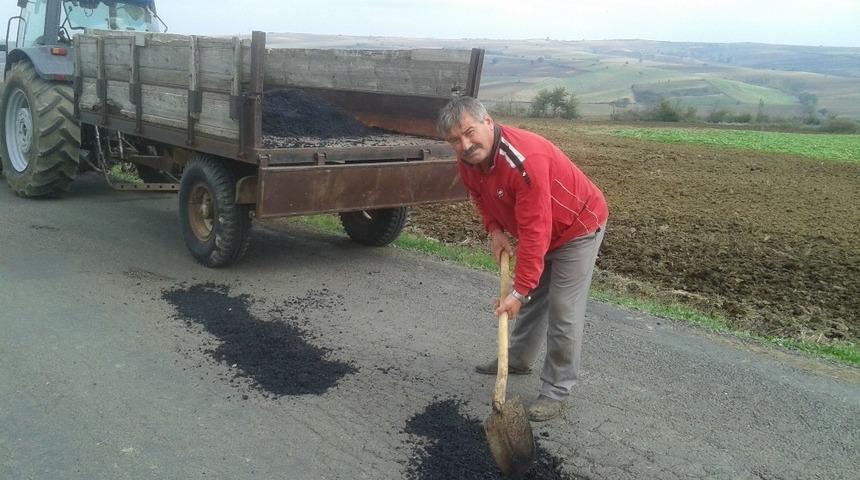 Muhtar k&uuml;reği eline alıp yola yama yaptı